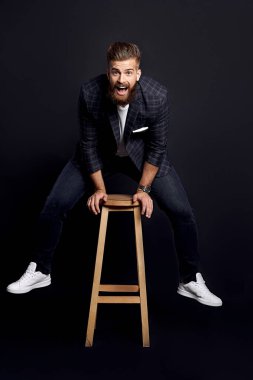 Deliriyorum. Siyah arka planda poz verirken bağıran ve kameraya bakan çekici bir genç..