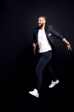 Tam boy fotoğraf, işe giderken sakallı, genç bir bilişim elemanı, siyahlar içinde izole edilmiş.