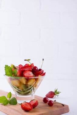 Beyaz masa arka plan üzerinde cam kapta taze lezzetli karışımı meyve salatası. Sağlıklı vitamin kahvaltı