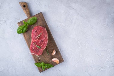 Çiğ et. Bir kesme tahtası Yeşiller ve baharat ile ham sığır eti biftek.