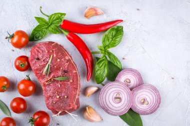 Çiğ taze et biftek ve baharat baharat gri beton zemin üst görüntüleyin. Kopya alanı.