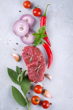 Çiğ taze et biftek ve baharat baharat gri beton zemin üst görüntüleyin. Kopya alanı.