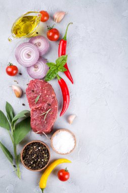 Çiğ taze et biftek ve baharat baharat gri beton zemin üst görüntüleyin. Kopya alanı.