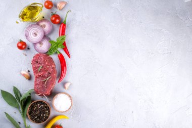 Çiğ taze et biftek ve baharat baharat gri beton zemin üst görüntüleyin. Kopya alanı.