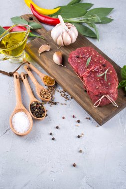 Çiğ taze et biftek ve baharat baharat gri beton zemin üst görüntüleyin. Kopya alanı.