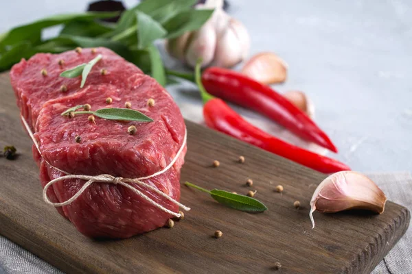 Kesme tahtası üzerinde yemek pişirmek için malzemelerle çiğ Dana biftek . 