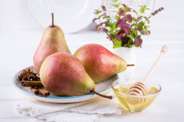 Taze, olgun organik tatlı armut tabak tarçın, Anason yıldız ve ballı beyaz mutfak masası üzerinde. 