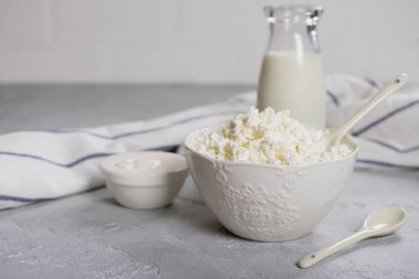 Organik tarım süzme peynir, lor bir beyaz seramik kase, ekşi krema ve bir şişe süt