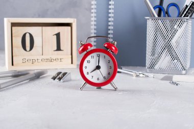 1 Eylül. Ahşap takvim, okul malzemeleri Grup, gri bir tablo üzerinde kırmızı çalar saat. Geri okul kavramı.
