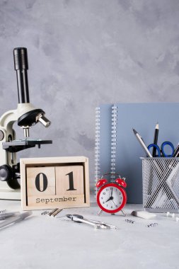 Okula dönüş. Grup okul malzemeleri, kırmızı alarm clock, mikroskop ve ahşap takvim tarihi 1 Eylül ile. Eğitim kavramı