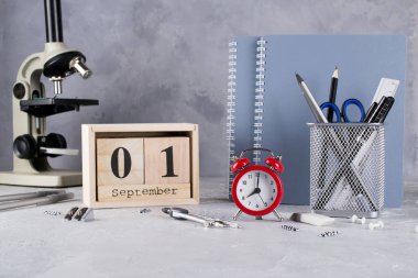 Okula dönüş. Grup okul malzemeleri, kırmızı alarm clock, mikroskop ve ahşap takvim tarihi 1 Eylül ile. Eğitim kavramı