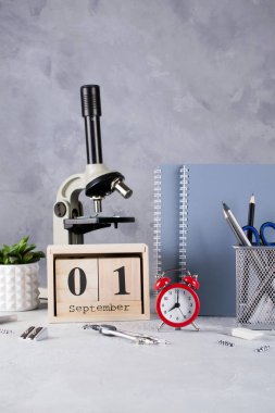 Okula dönüş. Grup okul malzemeleri, kırmızı alarm clock, mikroskop ve ahşap takvim tarihi 1 Eylül ile. Eğitim kavramı