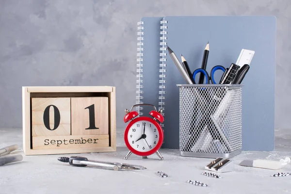 1 Eylül. Ahşap takvim, okul malzemeleri Grup, gri bir tablo üzerinde kırmızı çalar saat. Geri okul kavramı.