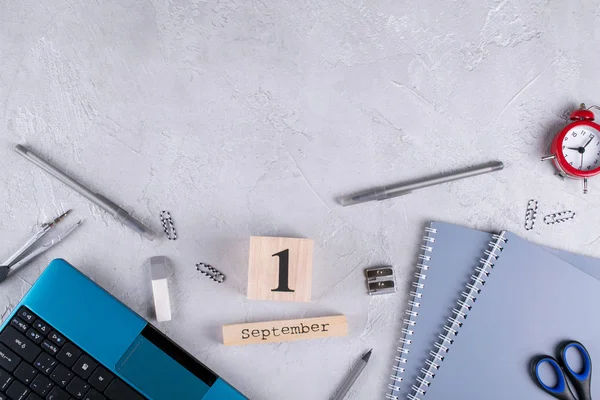 Dizüstü bilgisayar, kırmızı çalar saat ve malzemeleri, ahşap takvim tarihi 1 Eylül ile. bir gri beton masa üzerine. Geri okul kavramı. 