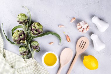 Yeşil olgun ham enginar kafaları pişirmeye hazır. Enginar ve malzemeler sarımsak, limon ve zeytin yağı
