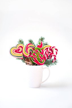 Kupası köknar ağacı dalı ve beyaz arka plan üzerinde izole Noel ağacı şeklinde renkli lolipop. tebrik kartı