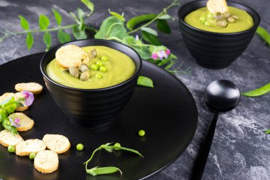 Ev yapımı yeşil bahar bezelye çorbası, kabak çekirdeği, kruton ile tepesinde. Karanlık taş arka plan üzerinde