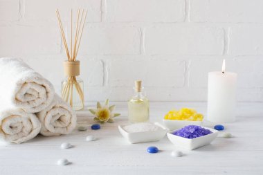 Spa sağlık ürünleri beyaz arka plan üzerinde bileşimi. havlu, beyaz zambak, deniz tuzu, banyo yağı, vücut scrub şeker ve mum 