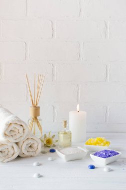 Spa sağlık ürünleri beyaz arka plan üzerinde bileşimi. havlu, beyaz zambak, deniz tuzu, banyo yağı, vücut scrub şeker ve mum 