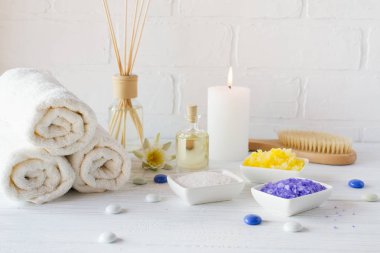 Spa sağlık ürünleri beyaz arka plan üzerinde bileşimi. havlu, beyaz zambak, deniz tuzu, banyo yağı, vücut scrub şeker ve mum 