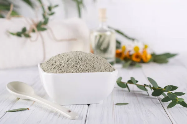 Preparing cosmetic mud mask with various skincare products. Dry clay powder in bowl. Natural cosmetics for home or salon spa treatment. On white background.