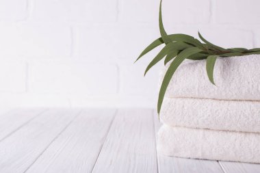 Ahşap masa Spa kompozisyonu. Üç beyaz kabarık banyo havlusu okaliptüs Şubesi ile yığını. Kopya alanı