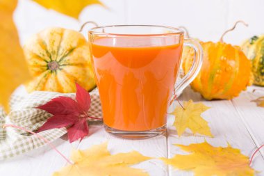 Geleneksel sonbahar içki. Cam bardak kabak suyu, kabak ve düşmüş akçaağaç yaprağı