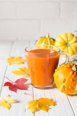 Geleneksel sonbahar içki. Cam bardak kabak suyu, kabak ve düşmüş akçaağaç yaprağı