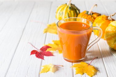 Taze kabak suyu cam fincan, kabak ve düşmüş akçaağaç yaprakları. Sonbahar içecek konsepti