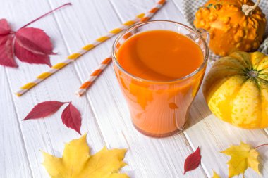 Taze kabak suyu cam fincan, kabak ve düşmüş akçaağaç yaprakları. Sonbahar içecek konsepti