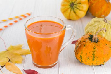 Geleneksel sonbahar içki. Cam bardak kabak suyu, kabak ve düşmüş akçaağaç yaprakları