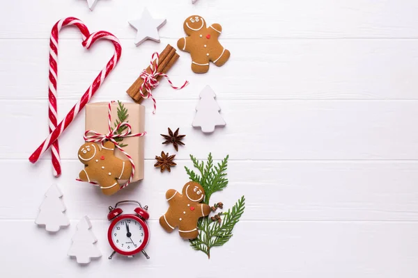Baking time. Preparation for the holidays. Christmas or New Year background with cookies, ribbon, candy cane, Christmas ornaments, gift box, pine cones and fir branches red alarm clock