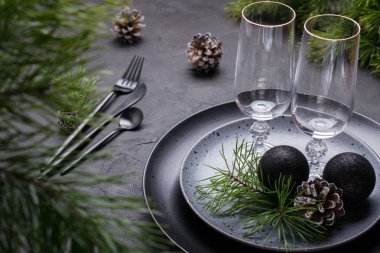 Karanlık Noel tablo ayarını tasarım. Siyah plakalar, şampanya bardağı, çatal ve bıçak koymak peçete, köknar dalı, Noel süsleri