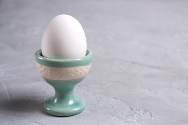 Beyaz tavuk yumurta seramik standında. Bir gri beton zemin üzerinde.