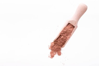 Yüz ve vücutta bir tahta kaşık kuru kırmızı kil maskesi. Beyaz bir arka plan üzerinde izole