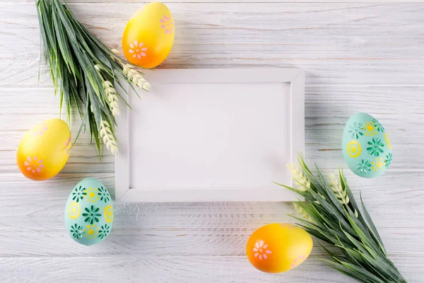 Easter mock up with photo frame.  Colorful easter eggs, and decorative wooden bunny. Celebration, holiday concept. Flat lay, top view, copy space