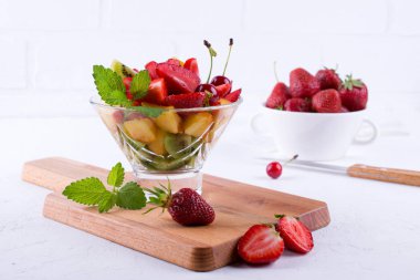 Beyaz masa arka plan üzerinde cam kapta taze lezzetli karışımı meyve salatası. Sağlıklı vitamin kahvaltı