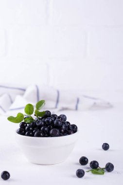 Beyaz arka plan, kopya alanı üzerinde beyaz kase taze ham organik çiftlik yabanmersini