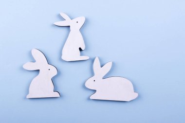 Pastel mavi zemin üzerine üstten görünüm üç beyaz ahşap Bunny. Kopya alanı