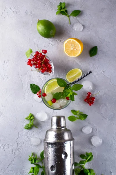 Cocktail shaker, lemon, lime, mint leaves , red currant  and  ice  for preparing a summer cocktail