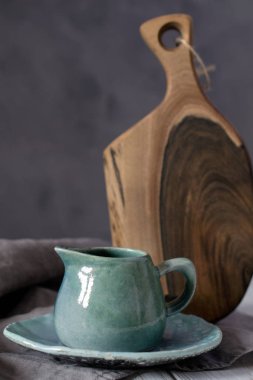 Doğal el işi dishware. Ahşap kahverengi kesme tahtası ve gri kumaş peçete ile seramik mavi krem kabı. Ülke, rustik tarzı