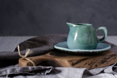 Doğal el işi dishware. Ahşap kahverengi kesme tahtası ve gri kumaş peçete ile seramik mavi krem kabı. Ülke, rustik tarzı