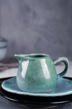 Ülke, rustik tarzı el sanatları mutfak eşyaları. Gri zemin üzerine mavi seramik krem kulplu testi