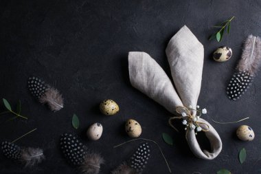 Paskalya tatili arka plan ile yumurta. Üstten Görünüm Bıldırcın yumurta, tüy ve tavşan kulakları keten peçete karanlık paslı arka plan üzerinde. Boşaltmak için metin