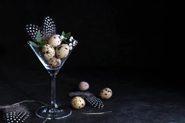 Idea of modern easter interior decoration.  Quail eggs in cocktail glass on dark rusty background. Copyspace for text