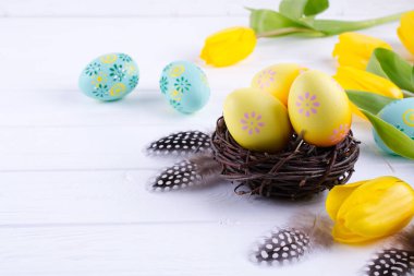Paskalya kavramı - dekoratif willow iç içe dekoratif yumurta ile beyaz arka plan üzerinde tüy. Boşaltmak için metin. düz lay