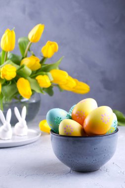 Renkli Paskalya yumurtaları ile kase; cam vazoda Sarı Lale çiçekler buket gri tablo Easter dekorasyon bahar; Paskalya iç dekorasyon