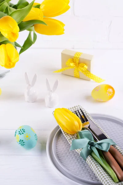 Spring Easter background for menu. Easter egg decoration, bunny, linen  napkin on plate and  kitchen cutlery on white wooden table.