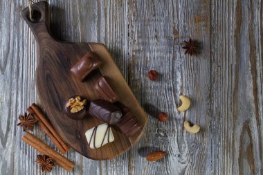 Rustik ahşap tahta üzerinde farklı şekiller ve renkler çikolata. Atmosferik gıda fotoğraf