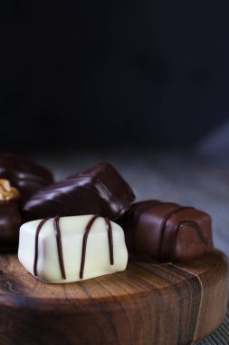 Siyah bir rustik ahşap TABL yerleştirilen bir doğrama tahtasında farklı şekiller ve renkler çikolata closeup